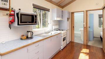 A modern kitchen with white cabinets, a microwave, a gas stove, and a sink.