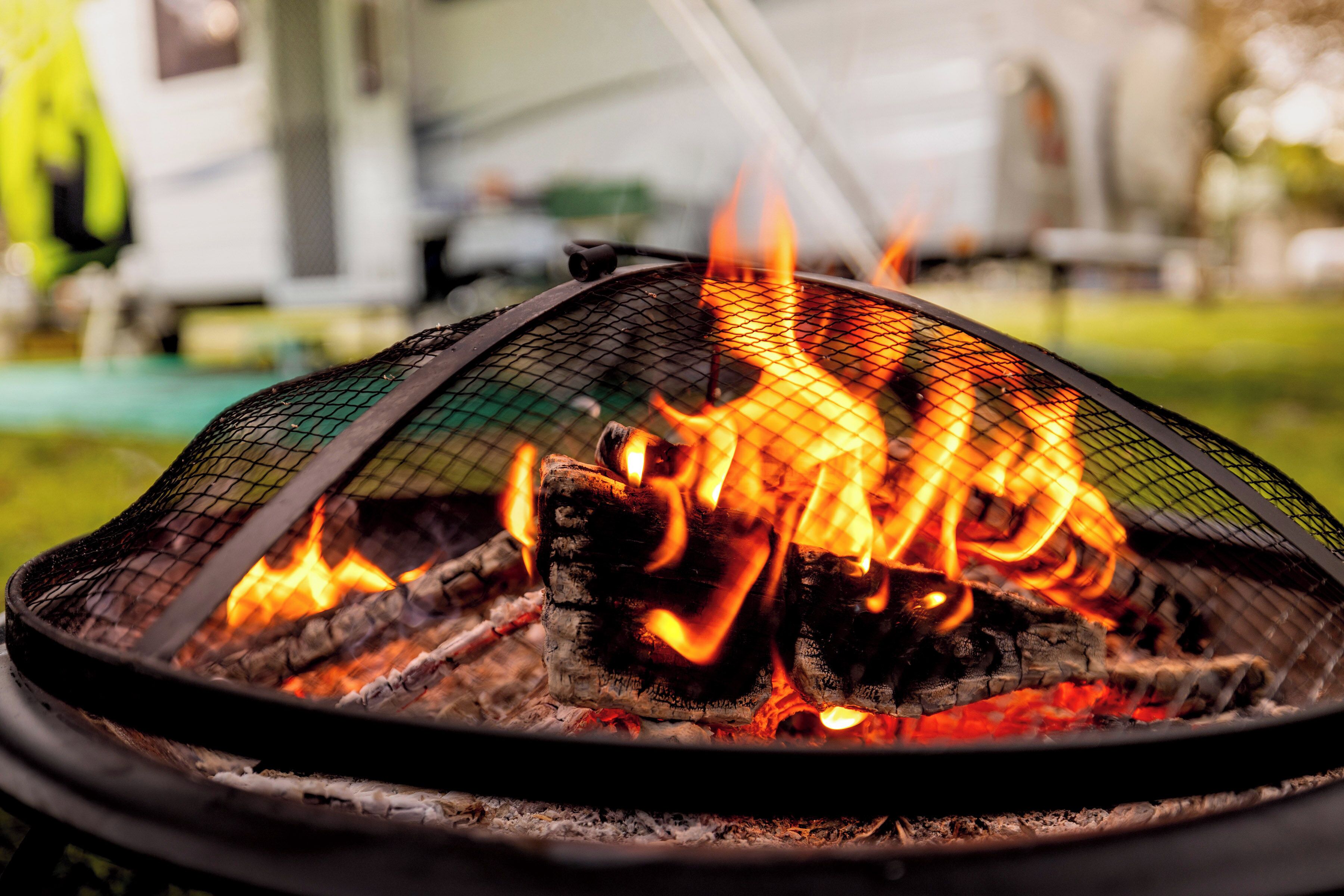 A close-up of a fire pit with burning logs and flames.