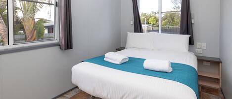 Una habitación de hotel con cama, ventana y vista a palmeras.