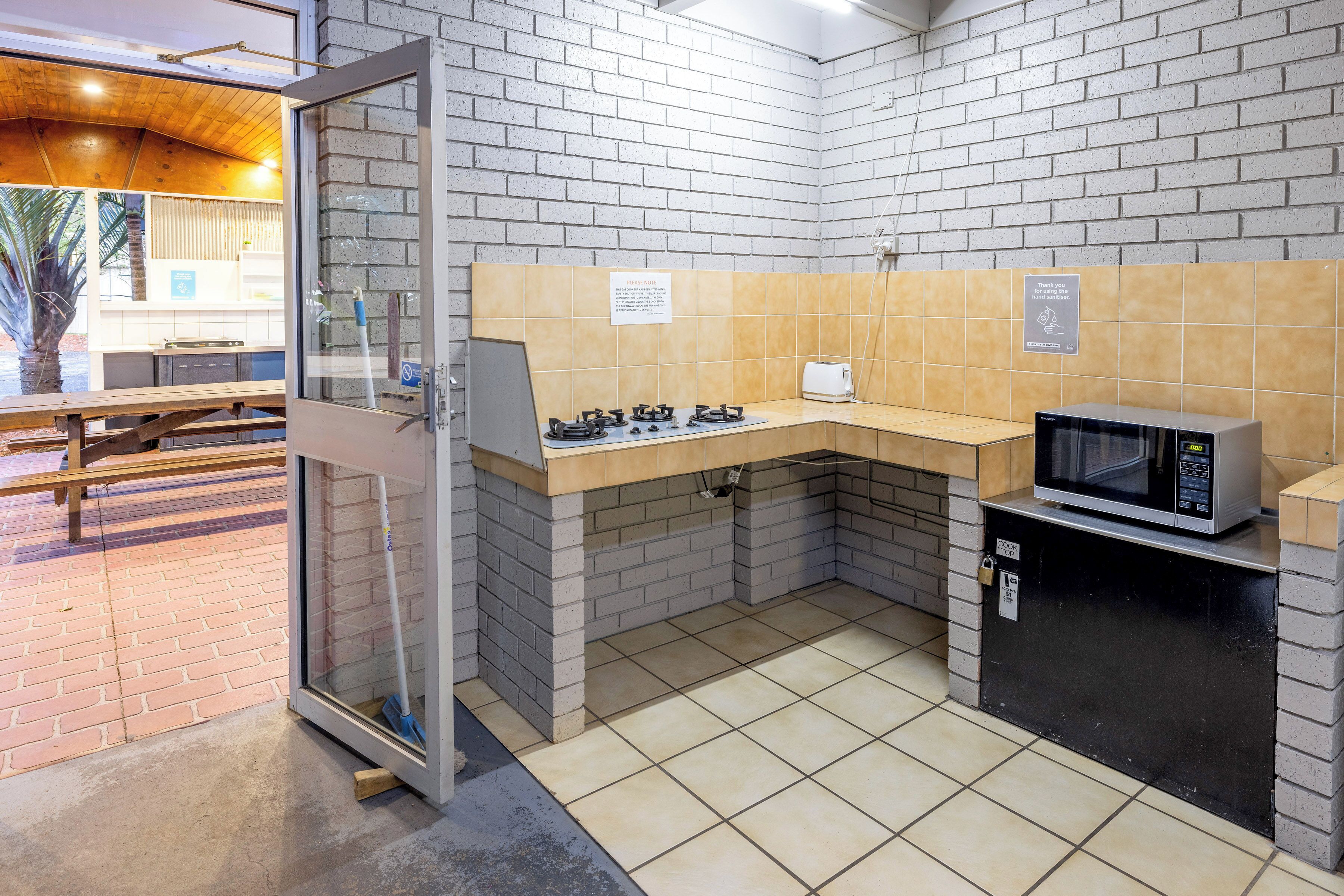 A compact kitchen with a microwave, gas stove, and a sink.