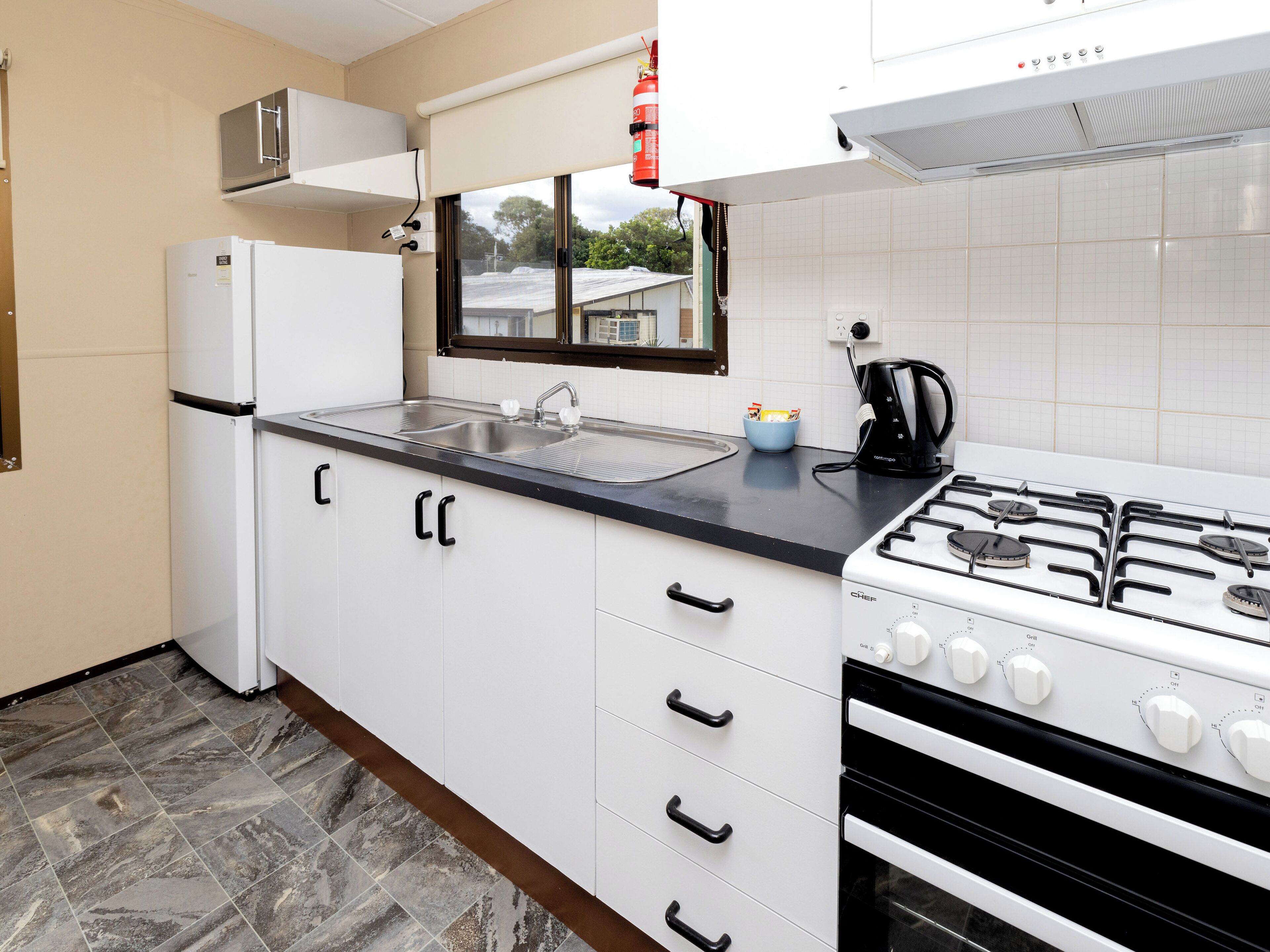 A compact kitchen with a gas stove, a built-in oven, a refrigerator, and a sink.