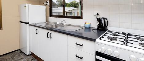 A compact kitchen with a gas stove, a built-in oven, a refrigerator, and a sink.