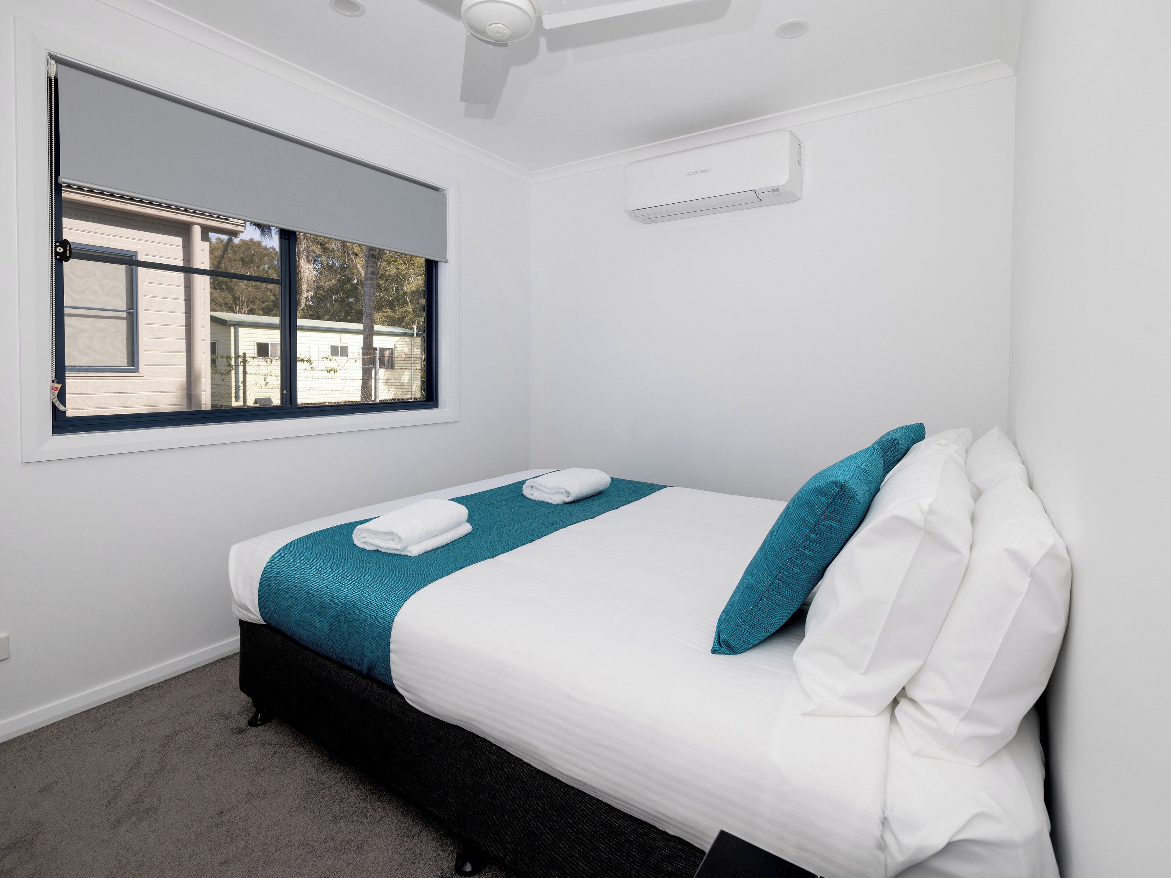 A bedroom with a bed, a window, and a ceiling fan.