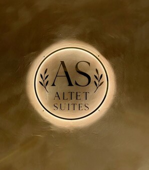 Un senyal rodó amb la inscripció 'AS ALLET SUITES' que indica el nom d'un hotel o allotjament.