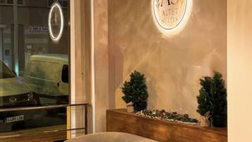 A reception area with a sofa, a wooden reception desk, a wall-mounted sign, and a hanging light fixture.
