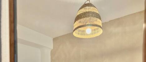 A hotel room with two beds, a wooden headboard, and a hanging light fixture.