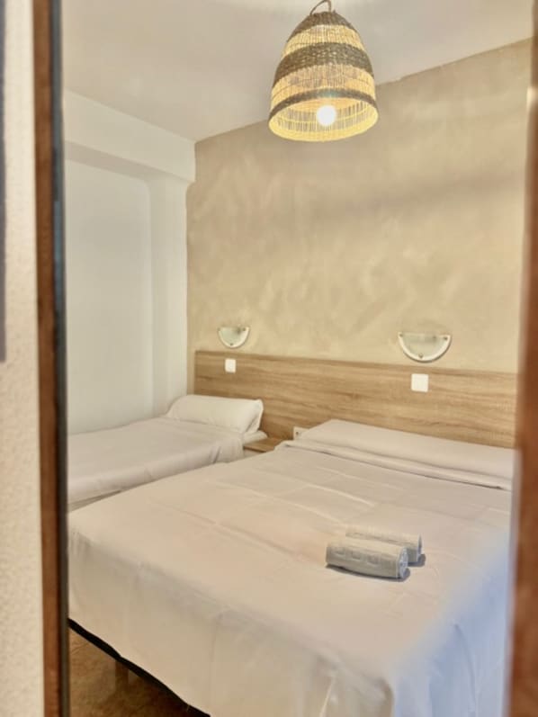 Habitación de hotel con dos camas, un cabecero de madera y una lámpara colgante.