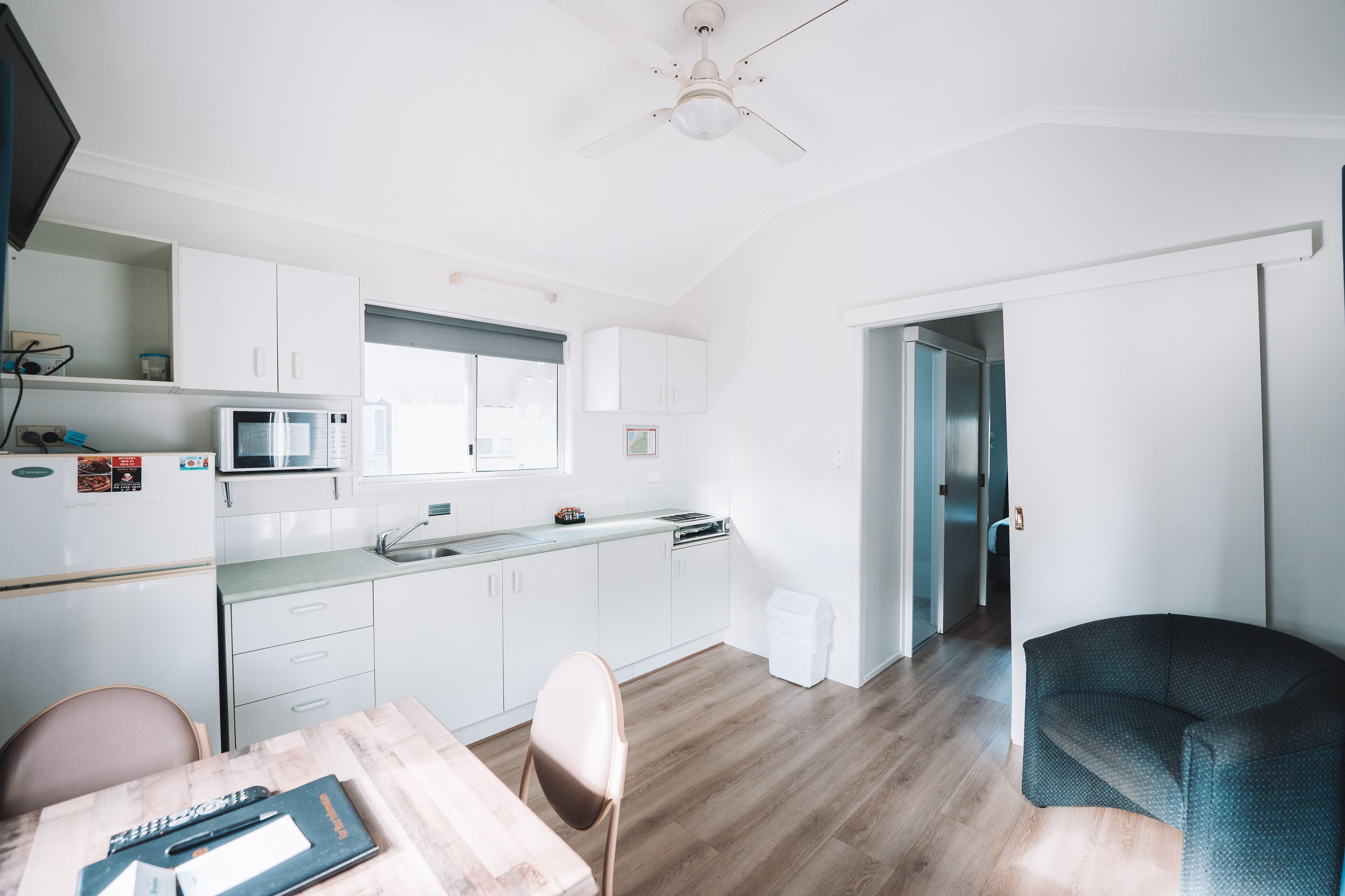 A modern kitchen with white cabinets, a microwave, and a dining area with a table and chairs.