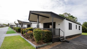 A row of mobile homes with covered porches and small gardens.