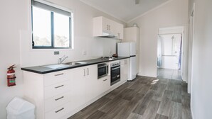 A modern kitchen with white cabinets, a black countertop, stainless steel appliances, and a window providing natural light. - BIG4 Rainbow Beach Holiday Park (Rainbow Beach)