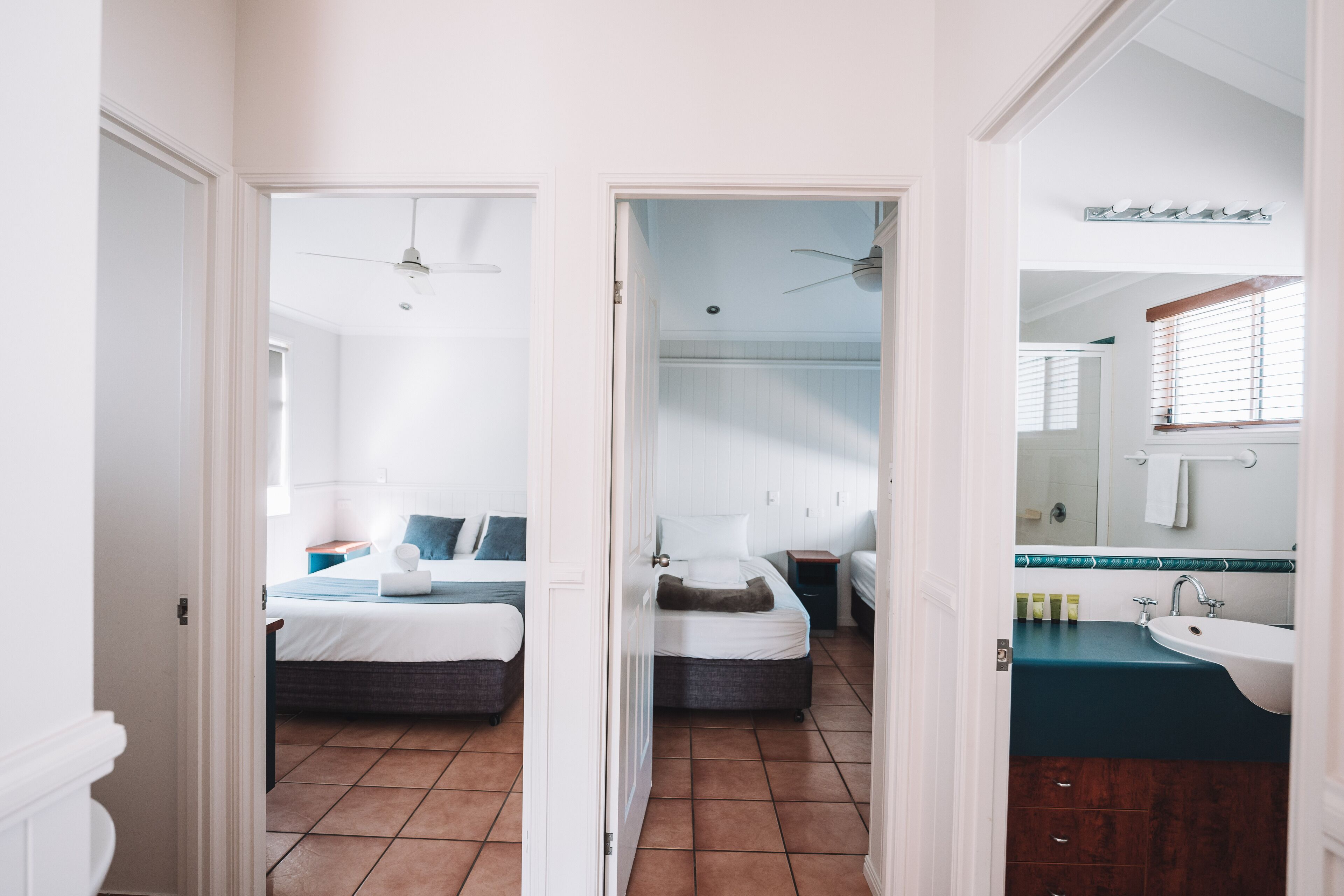 A hotel room with a bed, bedside table, and a bathroom with a sink and mirror.