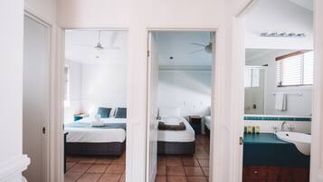 A hotel room with a bed, bedside table, and a bathroom with a sink and mirror.