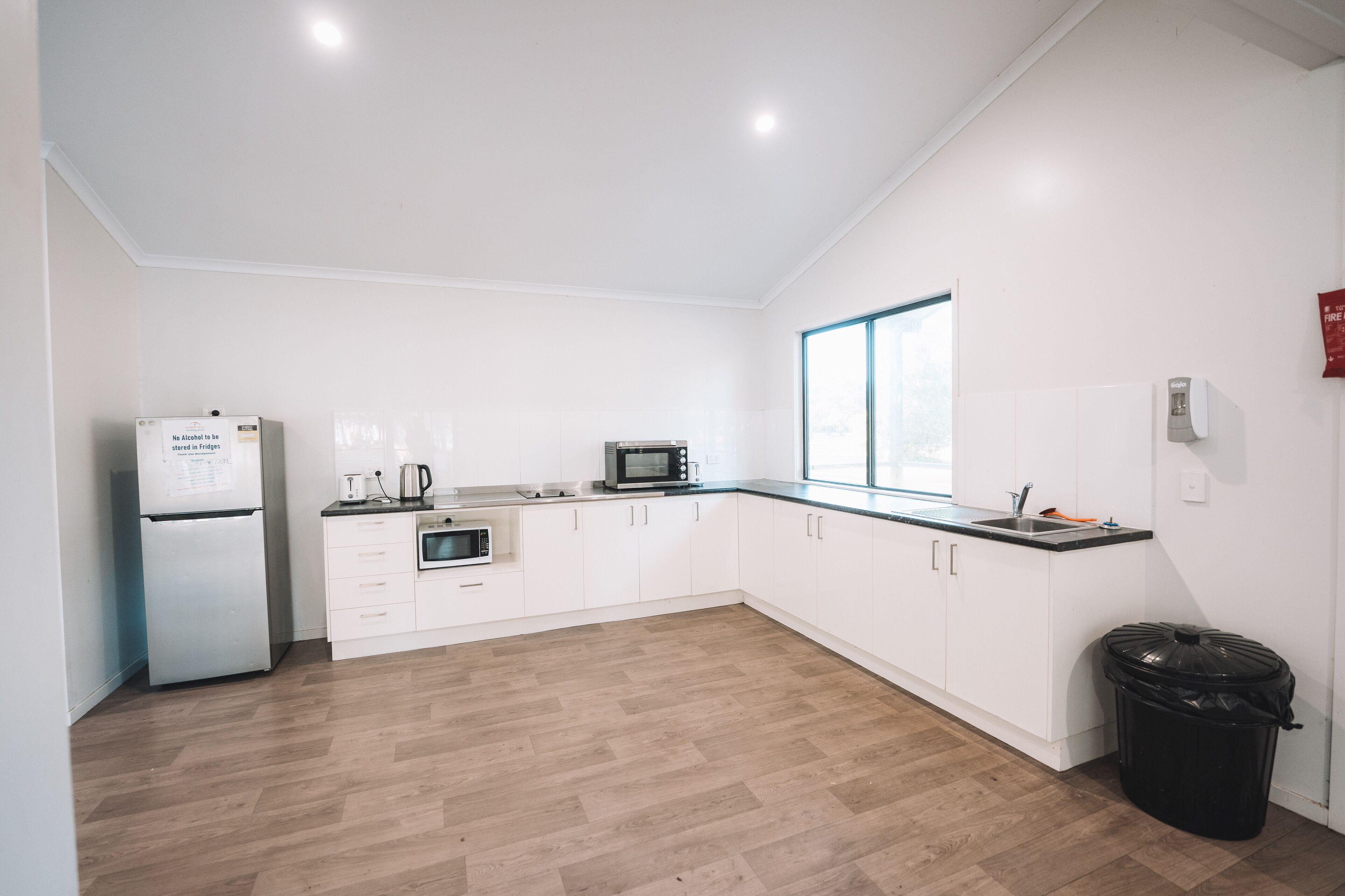 A modern kitchen with white cabinets, a refrigerator, a microwave, and a sink.