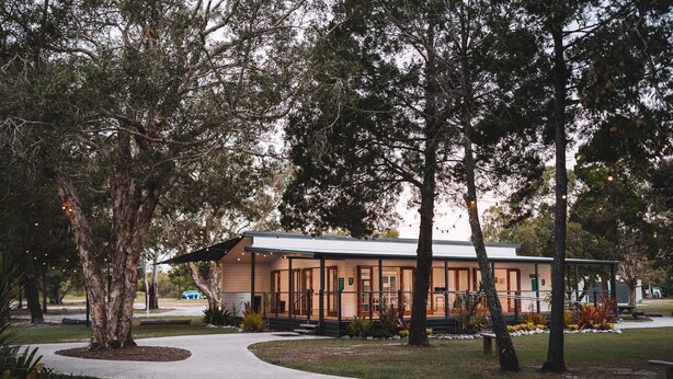 A modern building with a covered patio area, surrounded by mature trees and a well-maintained lawn. - BIG4 Rainbow Beach Holiday Park (Rainbow Beach)