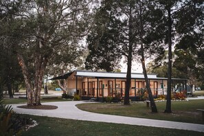 A modern building with a covered patio area, surrounded by mature trees and a well-maintained lawn. - BIG4 Rainbow Beach Holiday Park (Rainbow Beach)
