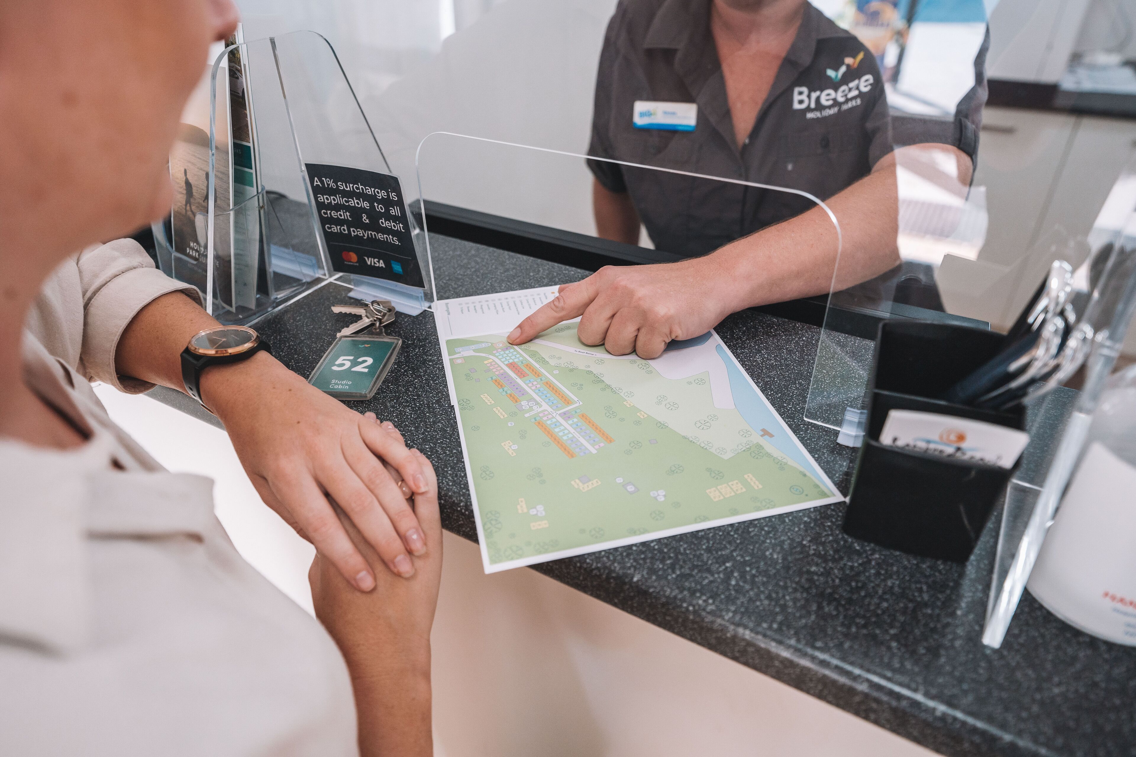 A person at a hotel reception desk with a map and a card reader.