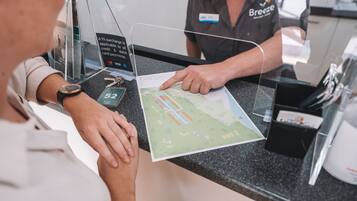 A person at a hotel reception desk with a map and a card reader.