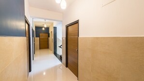 A hallway with a wooden door, a light fixture, and a view into another room. - Treebo Corner Stay, Coimbatore (Coimbatore)
