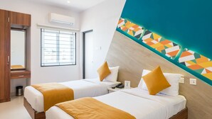 A hotel room with two beds, a wooden wardrobe, a window with blinds, an air conditioning unit, and a colorful geometric wall design. - Treebo Corner Stay, Coimbatore (Coimbatore)