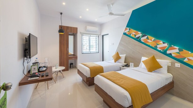 A hotel room with two beds, a desk with a computer, a TV, and a window with blinds. - Treebo Corner Stay, Coimbatore (Coimbatore)