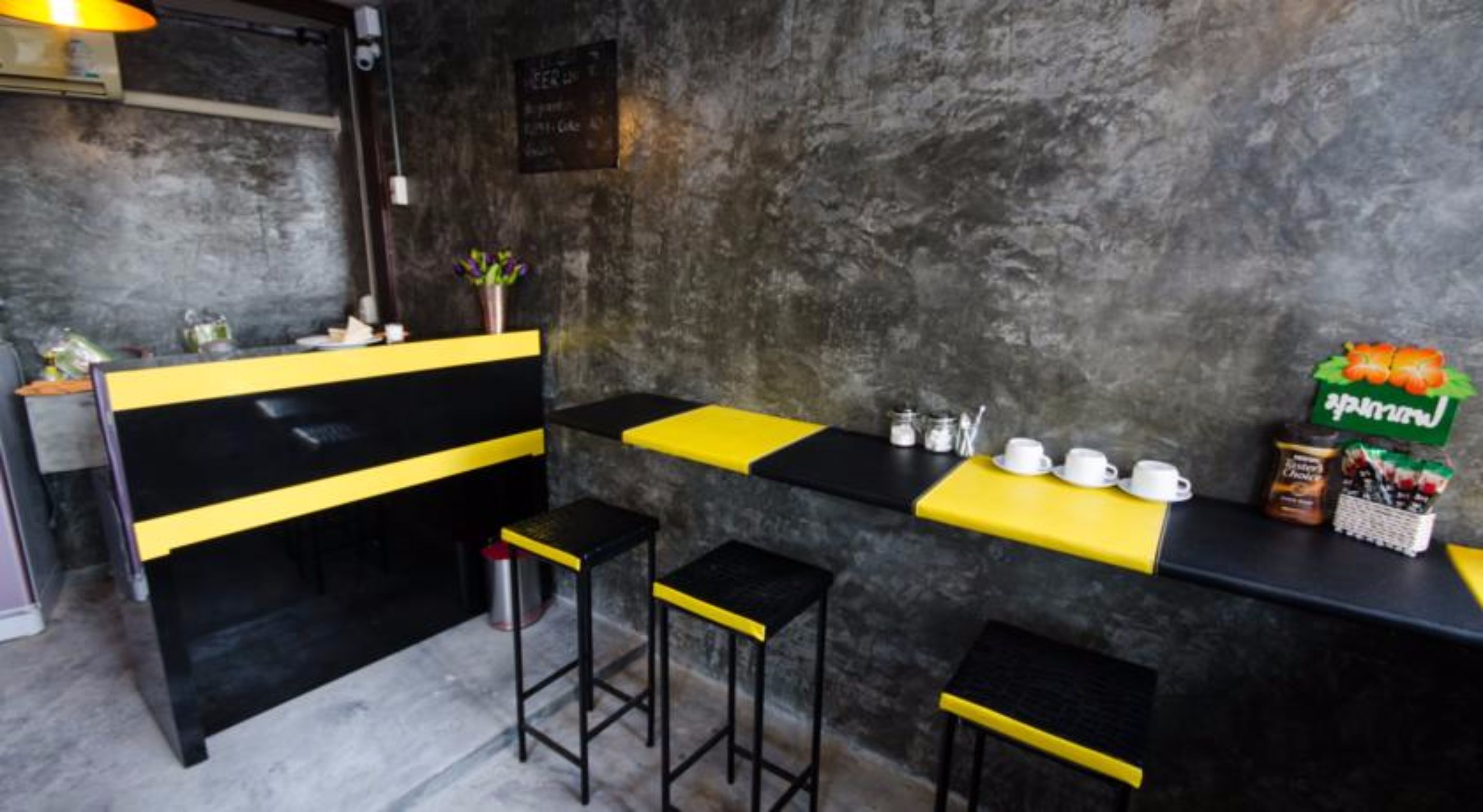 A bar area with a black and yellow counter, stools, and a wall-mounted sign.