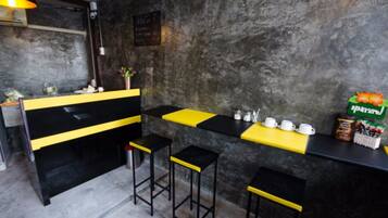 A bar area with a black and yellow counter, stools, and a wall-mounted sign.