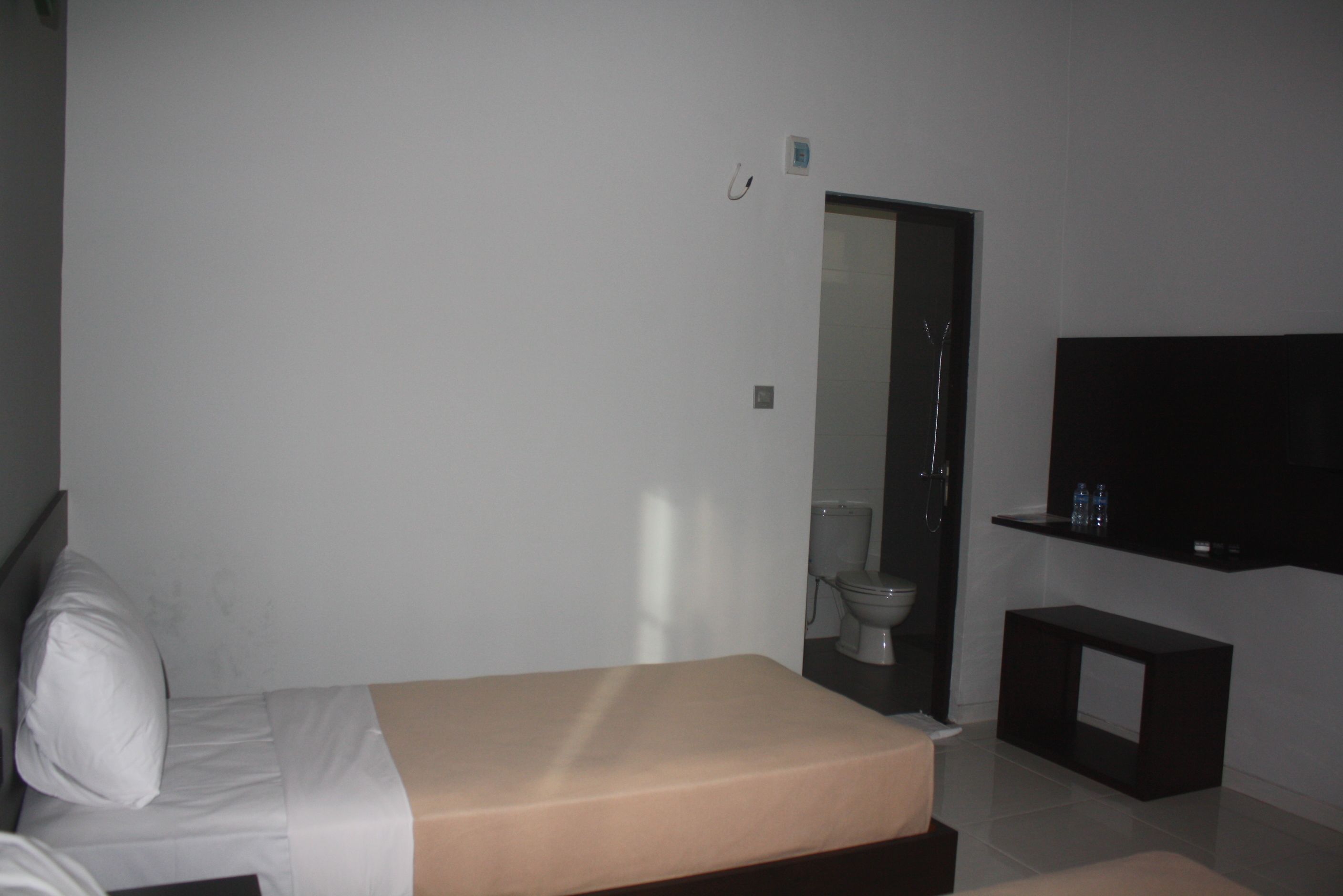 A bedroom with a bed, a television, a small table, and a mirror.