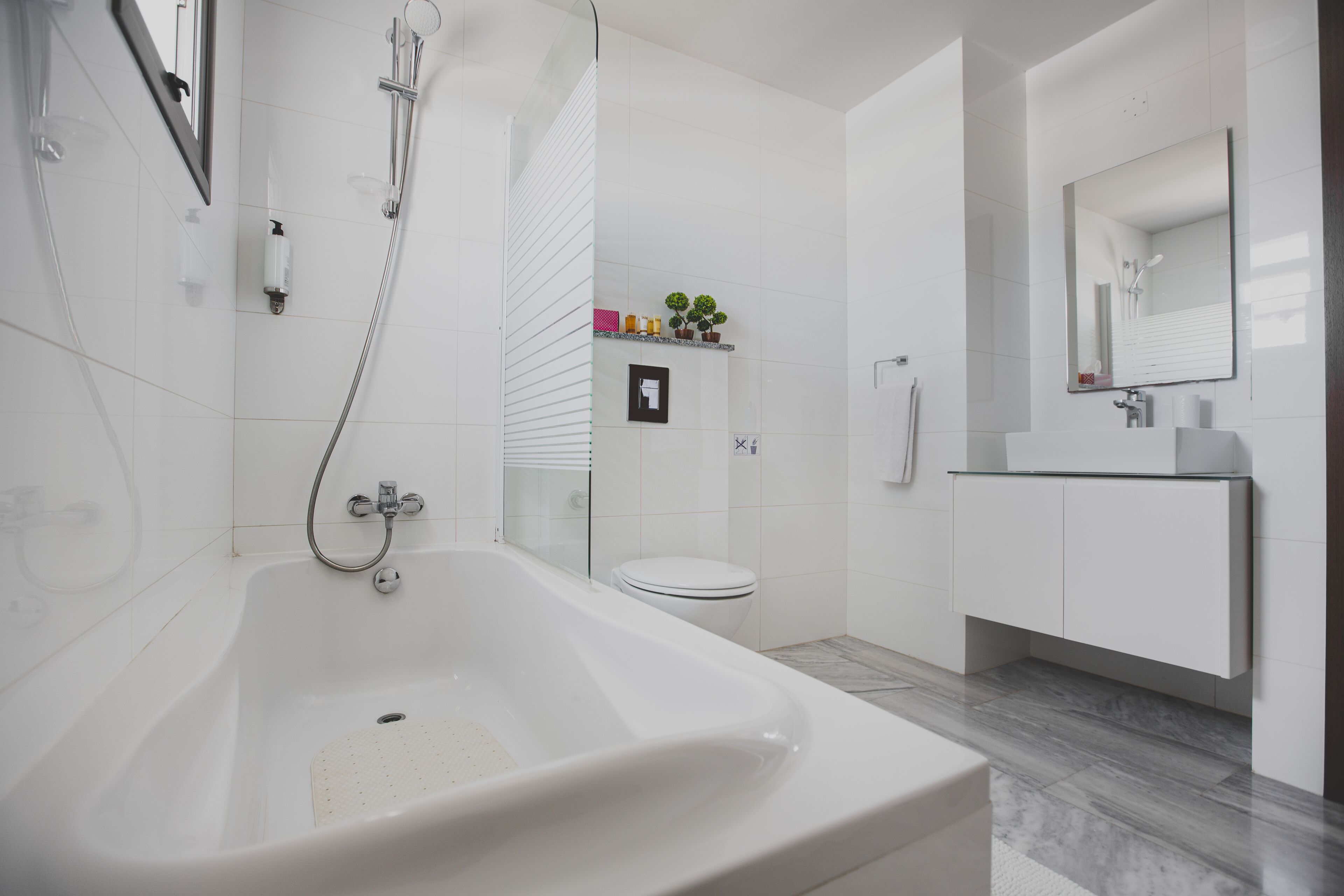 Un bagno moderno con una vasca freestanding, cabina doccia in vetro, un water e un mobile lavabo con specchio.