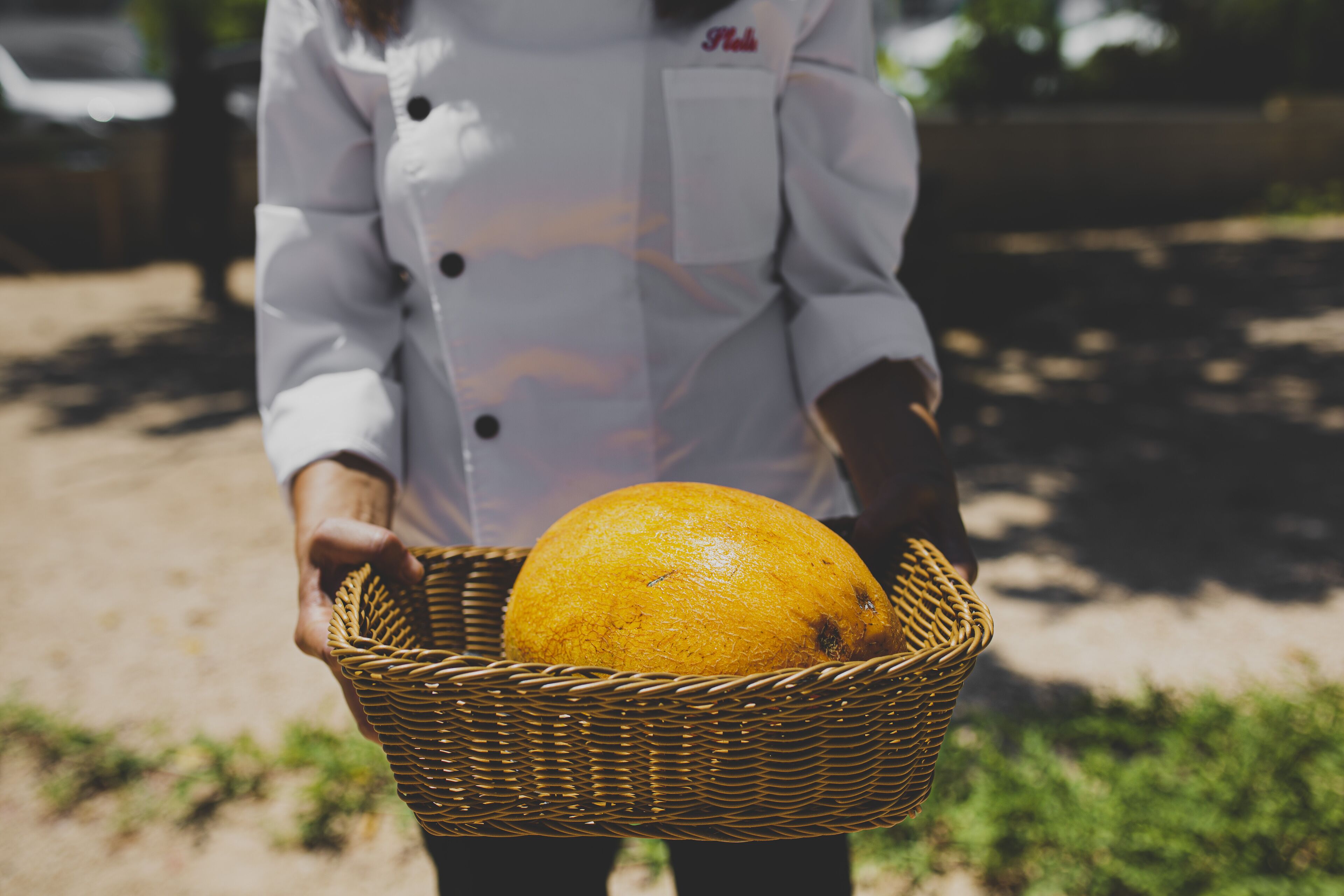 A person holding a wicker basket with an orange.
