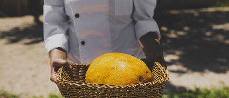 Une personne tenant un panier en osier contenant une orange.
