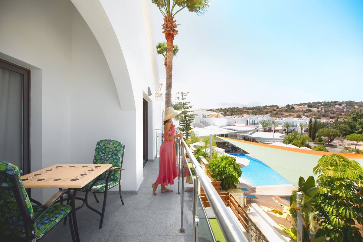 Un balcón con piscina, sillas y vistas del paisaje circundante.