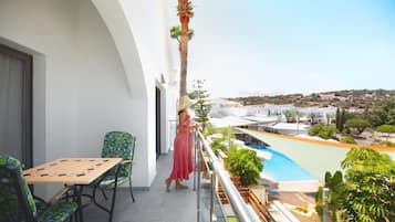 Ein Balkon mit Pool, Stühlen und Blick auf die umliegende Landschaft.