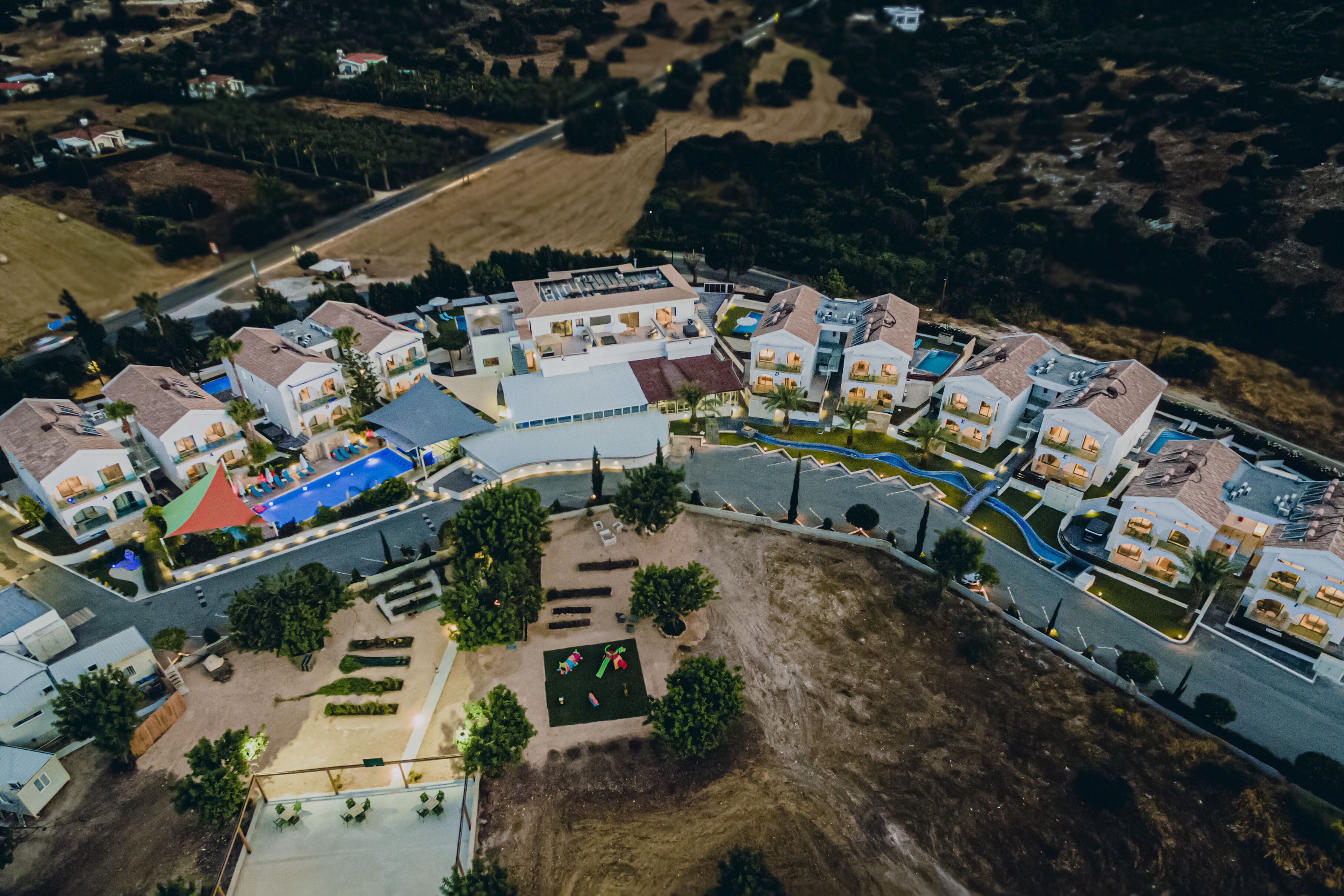 Vista aérea de una zona residencial con casas modernas, una piscina y jardines ajardinados.