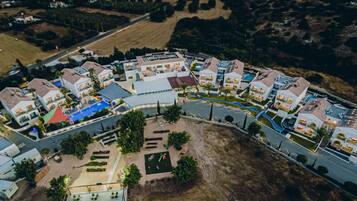 Vista aérea de una zona residencial con casas modernas, una piscina y jardines ajardinados.