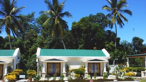 A resort with two white buildings with green roofs, surrounded by lush greenery and palm trees. - Saara Hotel (Mahajanga)