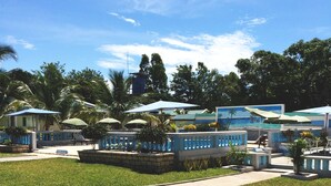 A resort with outdoor seating areas, palm trees, and a pool. - Saara Hotel (Mahajanga)