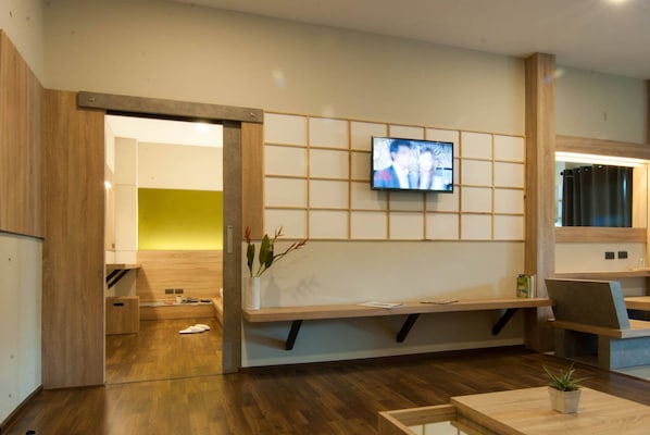 A reception area with a wooden bench, a television mounted on a wall, and a small table with a plant.