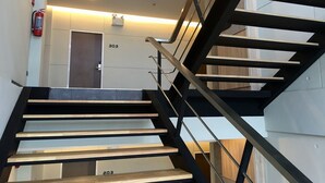 Un escalier moderne avec une rampe en métal noir et des marches en bois.