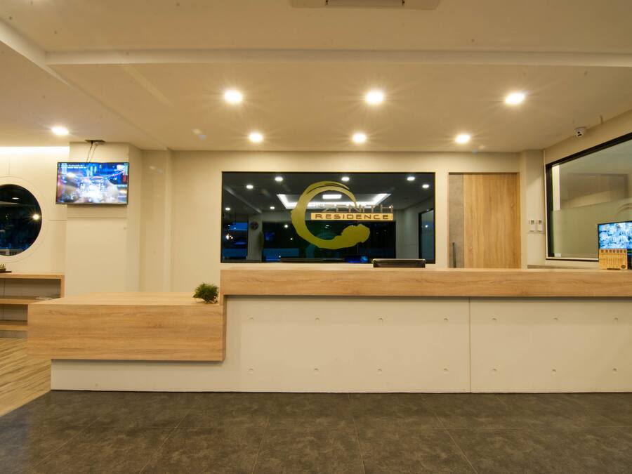 A reception area with a wooden reception desk, a large logo on the wall, and two televisions mounted on the wall.