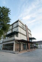 Un edificio de varios pisos con un diseño moderno, con amplios ventanales y un área de entrada techada.