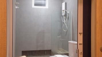 A bathroom with a shower, toilet, and a towel stack.