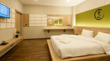 Quarto de hotel moderno com cama de madeira, TV de tela plana, escrivaninha de madeira e parede verde decorativa.