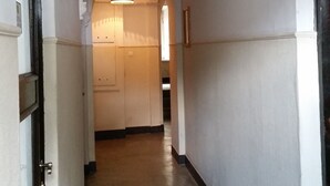 A hallway with white walls and a ceiling with a circular light fixture. There are doors on both sides of the hallway. - Old Town Art Apartment (Warsaw)