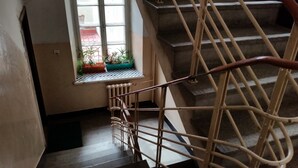 A staircase with a handrail, a window with potted plants, and a radiator. - Old Town Art Apartment (Warsaw)