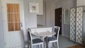 A room with a white door, a small table with two chairs, a framed picture on the wall, and a patterned door. - Old Town Art Apartment (Warsaw)