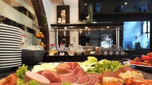 Un bufé con diferentes carnes, quesos y frutas.