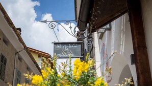 A narrow street with a sign for "histo hotel la scua reectorum" and a building with a mural. - Historic Hotel La Stua (Cavalese)