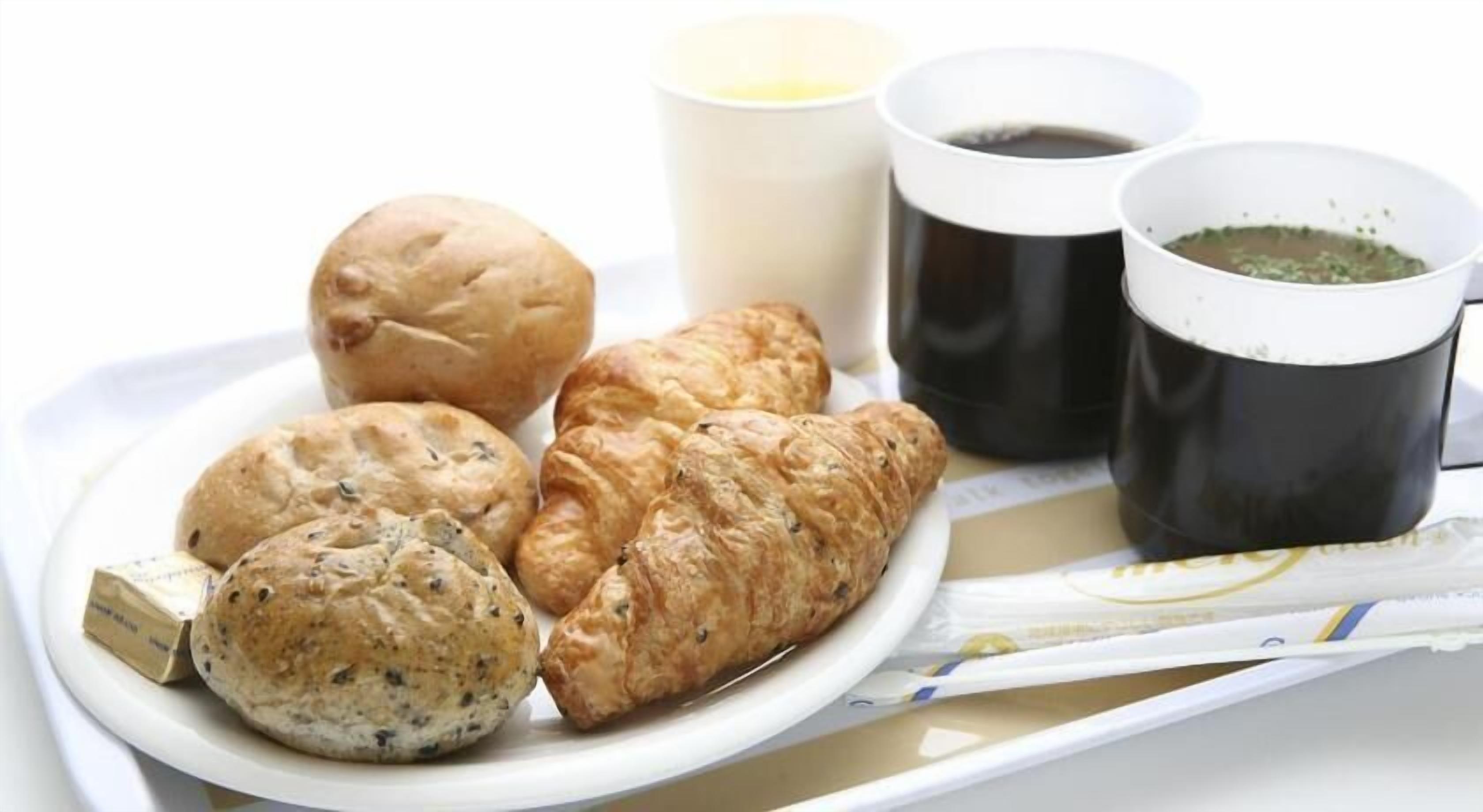 Ein Tablett mit Gebäck, zwei Kaffeetassen und einer Rolle Küchenpapier.
