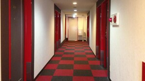A hotel corridor with red doors, checkered carpet, and a plain wall. - Hotel Select Inn Nagano (Nagano)