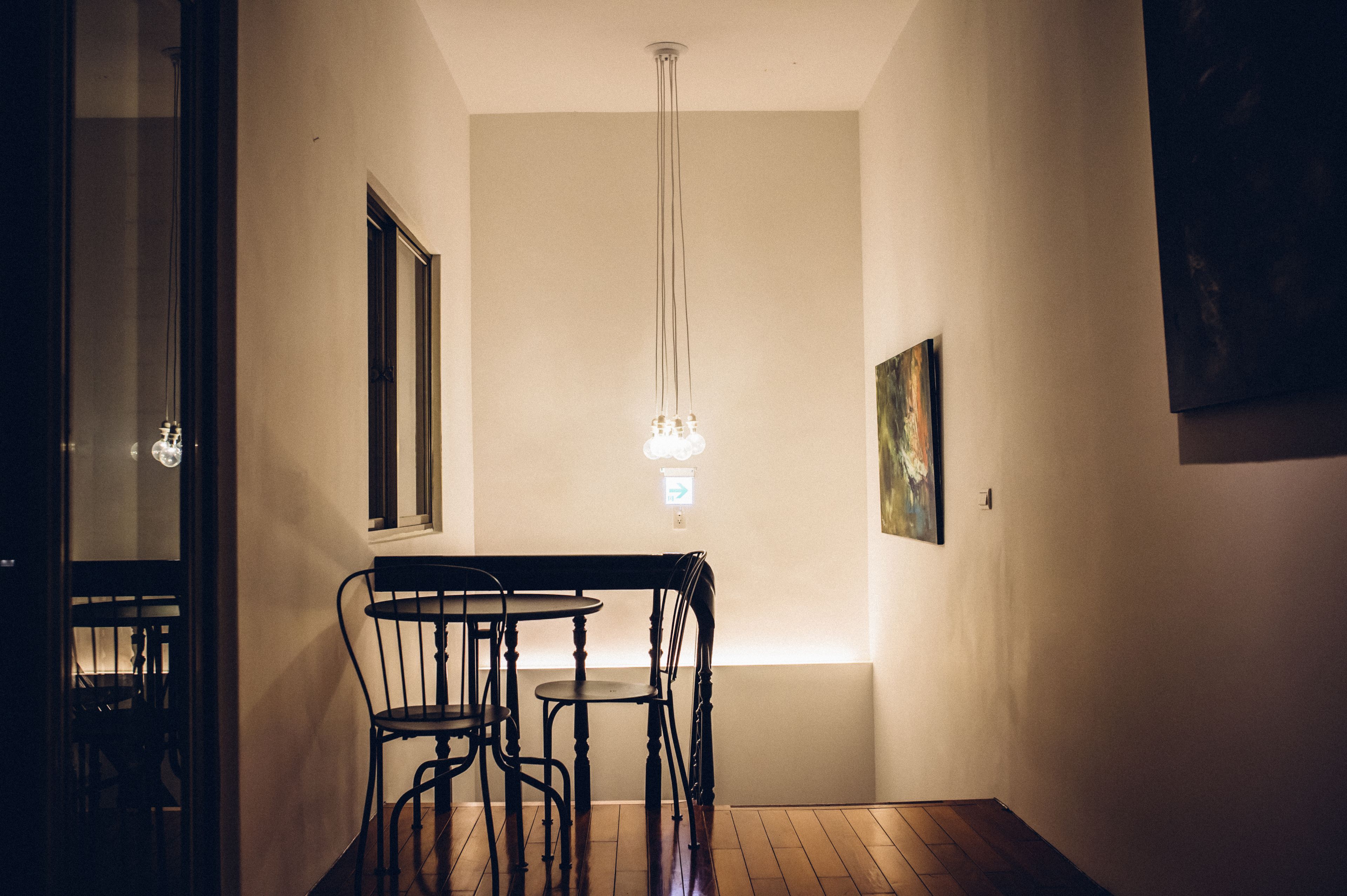 Un pasillo estrecho con una mesa de comedor y sillas, una lámpara colgante y un cuadro en la pared.